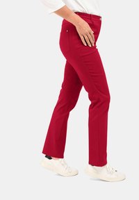 Rote Baumwollmischung-Hosen mit geradem Bein-Design, versehen mit Vorder- und Gesäßtaschen, kombiniert mit weißen Sneakern.