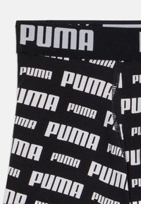 Črne bombažne kratke hlače z širokim črnim pasom, na katerem je napis "PUMA" v beli barvi. Telo hlač ima ponovljen vzorec belega logotipa.