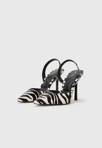 Pointed-toe slingback heels in black and white zebra-print fabric, featuring a sleek design and stiletto heel. Black inner lining.