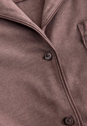 Chemise boutonnée marron en tissu doux et texturé. Dotée d'un col, de boutons sur le devant et d'une poche poitrine pour un design pratique.