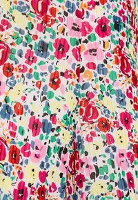 Tissu plissé floral avec un motif multicolore comprenant des nuances de rose, rouge, jaune, vert et bleu sur fond blanc.