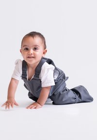 Graue wasserdichte Latzhose aus glattem Material, ausgestattet mit verstellbaren Trägern, entworfen für krabbelnde Kleinkinder vor einem schlichten Hintergrund.