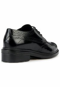 Chaussure habillée en cuir noir avec une finition brillante, des détails de brogue, un bout arrondi et une semelle en caoutchouc épaisse avec des rainures horizontales.