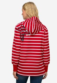 Felpa a righe rosse e bianche con cappuccio regolabile, dotata di dettagli grafici neri sul retro e polsini elasticizzati. Materiale in misto cotone.