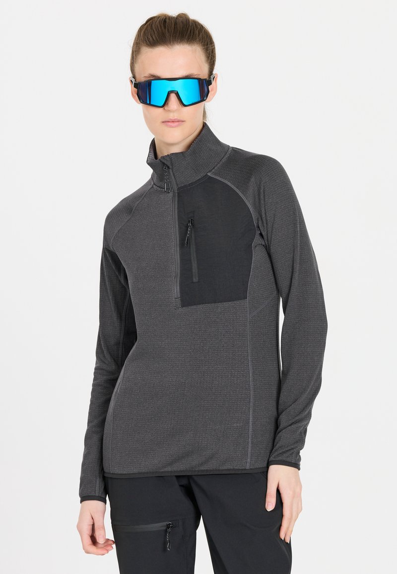 Grau melierter Pullover mit Reißverschluss, schwarzer Brusttasche, langen Ärmeln und strukturiertem Stoff. Das Modell trägt reflektierende blaue Sonnenbrillen.