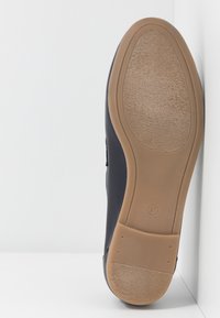 Semelle d'une chaussure noire avec une semelle extérieure en caoutchouc texturé marron clair, taille 37, présentée sur un arrière-plan blanc en angle.