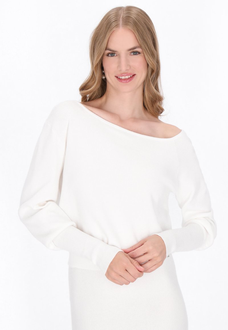 Suéter blanco de punto, con escote off-shoulder, mangas largas, puños acanalados y un corte relajado. Textura suave, diseño minimalista.