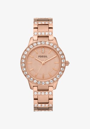 Montre-bracelet en or rose avec un boîtier orné de cristaux, un cadran rose texturé et un bracelet en maillons, affichant un design minimaliste et des index horaires.