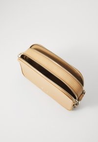 Borsa a mano in pelle color tan con due scomparti con zip, superficie liscia, forma arrotondata e design minimalista. Accenti in metallo visibili.