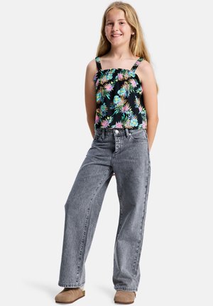 Czarny bezrękawnik z kolorowym kwiatowym wzorem; szare jeansy z wysokim stanem; beżowe buty wsuwane; długie proste włosy.