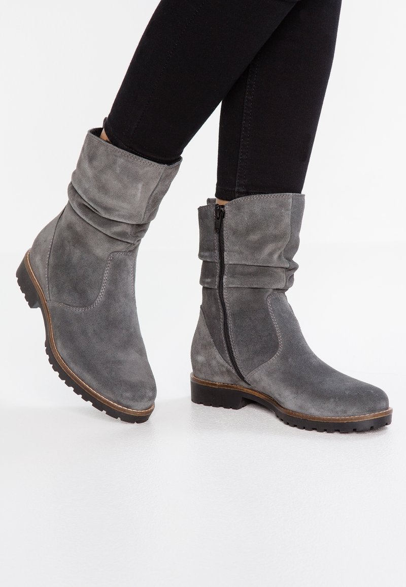 Bottines en suède gris avec des revers souples, fermeture éclair sur le côté et semelles en caoutchouc texturé. Le design présente des coutures subtiles et une forme de bout arrondi.