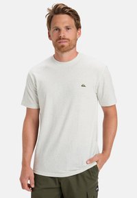Lys grå spraglet t-shirt lavet af blødt stof med en klassisk rund hals og et lille logo-patch på venstre bryst.