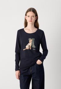 Marineblaue Langarmshirt mit einem Grafikdesign eines Hundes neben grünen Gummistiefeln. Hergestellt aus einem weichen, dehnbaren Material.