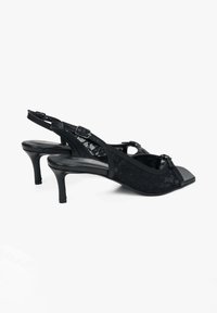 Czarne sandały na obcasie z kwadratowym noskiem, koronkowymi detalami i regulowanym zapięciem. Obcas typu stiletto ma wysokość 7 cm, gładkie skórzane akcenty.