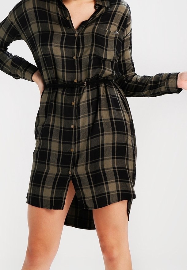 Robe chemise à carreaux en noir et olive, avec un devant à boutons, un col, des manches longues et une ceinture nouée à la taille avec un détail fente.