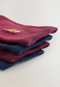 Vier opgestapelde sokken, met een bordeauxrode paar met rode strepen bovenaan en een marineblauw paar eronder, gemaakt van zacht, textuurvol materiaal.
