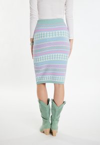 Pletená tyrkysová ceruzková sukňa s viacfarebnými horizontálnymi vzormi. Skombinovaná s mätovo zelenými perforovanými kovbojskými čižmami s blokovým opätkom.