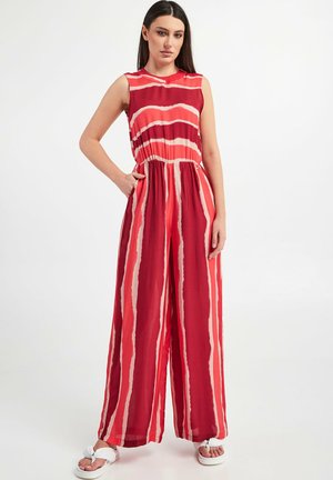 Tuta a righe rosse con design senza maniche, vita aderente e gambe larghe. Il materiale sembra leggero e fluido, con audaci accenti chiari.