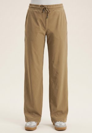 Khakikleurige casual broek met een elastische tailleband en trekkoord, gedragen met witte en grijze sneakers, van voren gezien.
