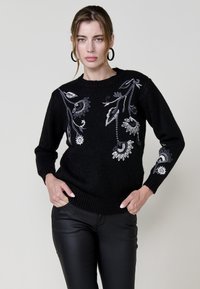 Maglione nero a maniche lunghe, con intricate ricami grigi di fiori e foglie sul davanti. Collo e orlo a coste.