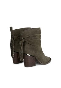 Oliwkowe zamszowe botki za kostkę z opadającą cholewką, frędzlami, ozdobnymi ćwiekami i masywnym brązowym drewnianym obcasem. Projekt otwartego palca.