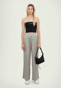 Μαύρο strapless τοπ με διακοσμητική γραμμή, γκρι παντελόνι σε φαρδιά γραμμή, λευκά sneakers και μικρή μαύρη τσάντα. Μινιμαλιστικός σχεδιασμός και μαλακά υφάσματα.