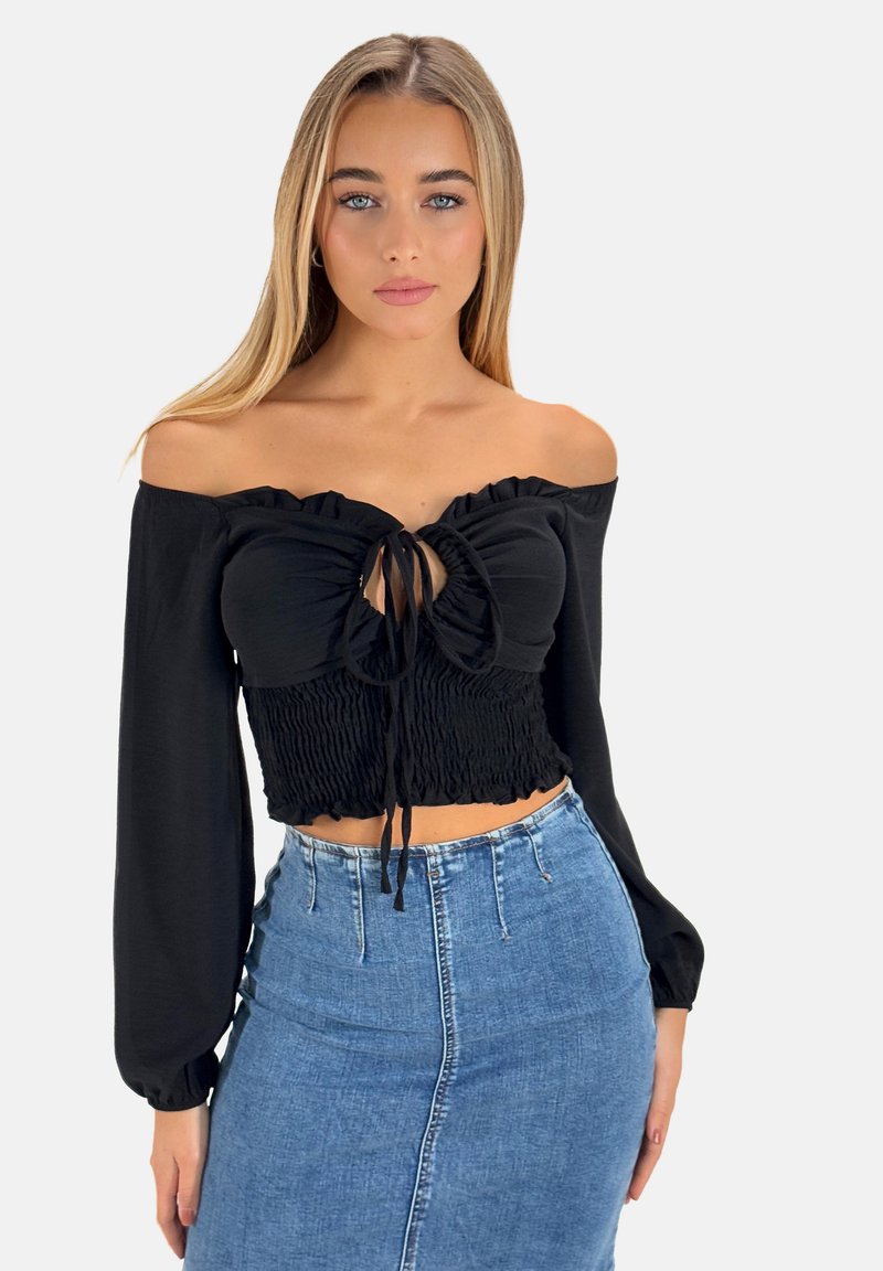 Schwarzes, schulterfreies Cropped-Top mit Rüschensaum, Kordelzugdetail und gerafftem Taillenbund, kombiniert mit einem hochgeschnittenen Jeansrock.