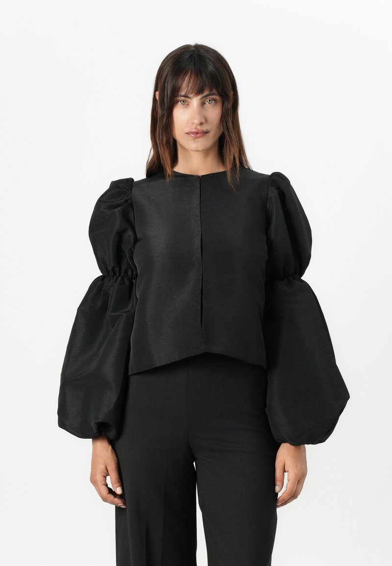 Černý zkrácený top s oversized, vypufovanými rukávy. Vyroben z hladké látky s matným povrchem, obsahuje jednoduchý, nezdobený design.