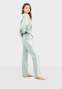 Licht mintgroen athleisure set met een cropped hoodie en bijpassende broek met witte zijstrepen, gemaakt van zachte, gestructureerde stof.