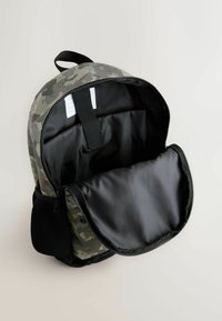 Rucksack im Tarnmuster mit Reißverschluss, schwarzer Innenauskleidung und einer vorderen Netz-Tasche. Gefertigt aus strapazierfähigem Material mit einem Schlaufengriff.
