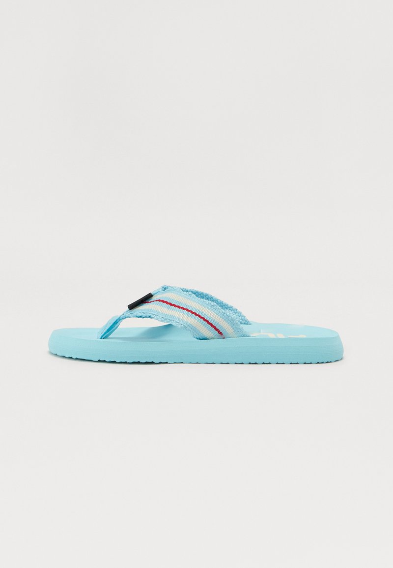 Čības ar gaiši zilu gumijas zoli ar teksturētu saķeri, izstrādātu siksniņu zilā un baltā krāsā ar sarkaniem akcentiem un melniem detaļām.