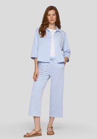 Blau-weiß gestreiftes Hemd und Hosen-Set aus leichtem Stoff. Das Hemd hat einen Kragen, Knöpfe undSeitentaschen; die Hose hat einen Kordelzug am Bund.