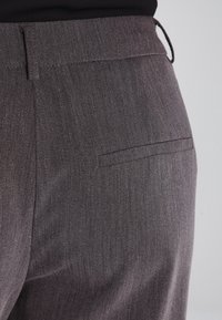 Dopasowane szare spodnie o gładkiej fakturze, z jedną tylną kieszenią i paskiem na szlufki.
