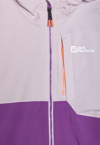 Veste violette et gris clair avec une fermeture éclair à l'avant avec un accent orange, un petit logo sur la poitrine et une capuche.
