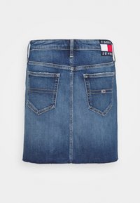 Jeanskjol i mörkblått med rak skärning, utrustad med två bakfickor och en logotyp på midjebandet. Slät textur, avslappnad design.