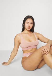 Vaaleanpunainen ribattuja bralette leveillä olkaimilla ja neliönmuotoisella kaula-aukolla, joka on yhdistetty yhteensopiviin korkeavyötäröisiin alushousuihin, sileä pinta ja istuva muotoilu.