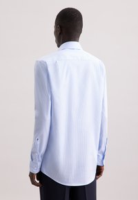 Camicia a righe blu chiaro con maniche lunghe, polsini con bottoni e colletto classico. Tessuto liscio e strutturato con una vestibilità comoda.