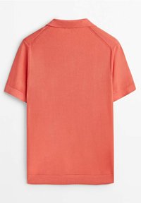 Polo à manches courtes corail avec coutures raglan et col, poignets et ourlet côtelés, présenté de dos sur fond blanc.