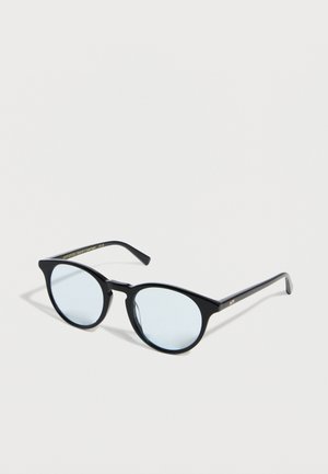 Black round eyeglasses with thin frames and light blue tinted lenses resting on a white surface.