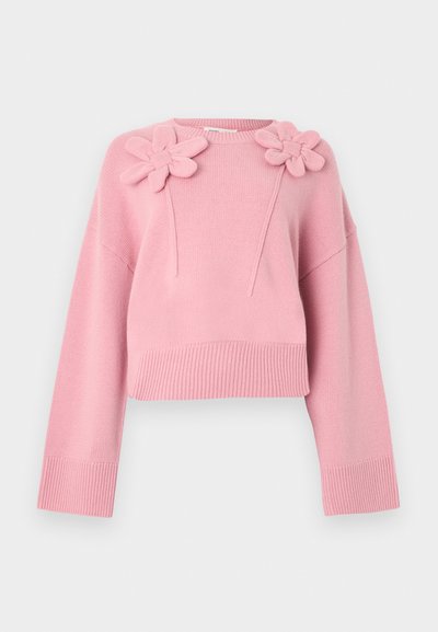 Ροζ κοντό πουλόβερ από απαλό πλεκτό ύφασμα. Διαθέτει δύο λουλουδάτες εφαρμογές στον ώμο, με φαρδιά μανίκια και ριμπ τελείωμα.