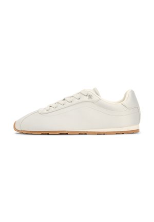 Beige lavtop sneaker med snørelukning, glat læderoverdel, minimal syning og lyst brunt gummisål, vist fra siden.