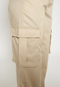 Beige cargobukser med en glat tekstur, med en sidelomme og lige ben. Fremstillet af letvægtsstof.