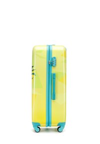 Valise rigide jaune avec un motif géométrique, dotée de zips et de roues turquoise vifs, ainsi qu'une poignée latérale pour un transport facile.