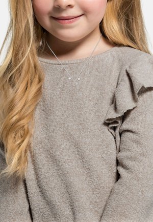 Silberne Halskette mit einem Herzanhänger und zwei kleinen Perlen, getragen über einem hellbraunen, strukturierten Pullover mit Rüschensleeves.