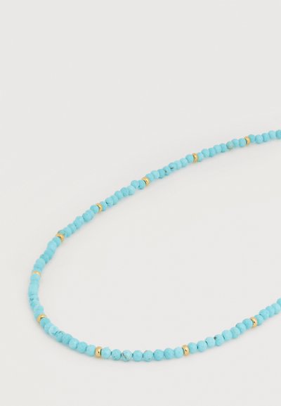 Λεπτό κολιέ με μικρές στρογγυλές τυρκουάζ χάντρες διαχωρισμένες από μικρές χρυσές χάντρες τοποθετημένες ομοιόμορφα σε ανοιχτό φόντο.