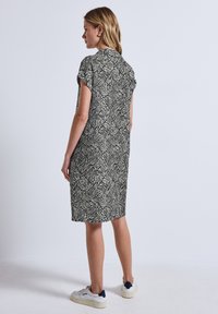 Robe à manches courtes en imprimé zèbre noir et crème, longueur genoux, coupe décontractée, avec une texture douce et un design droit.