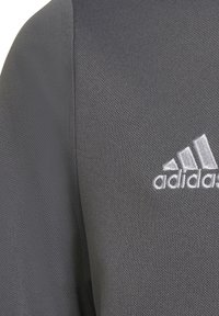 Sudadera deportiva gris con tejido texturizado, cuello redondo y logo de Adidas bordado en blanco en el lado izquierdo del pecho.