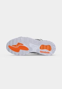 Λευκή και πορτοκαλί σόλα παπουτσιού Reebok με υφή πέλματος και λογότυπα της μάρκας, εμφανιζόμενη από κάτω σε απλό φόντο.