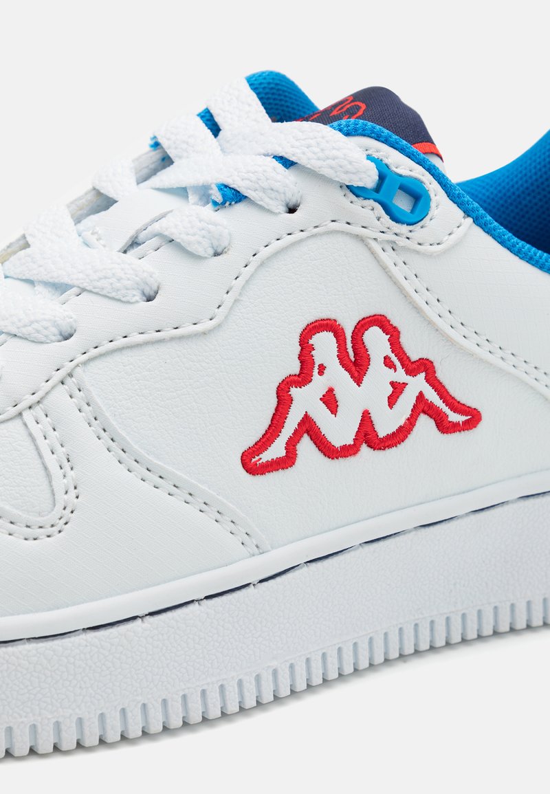 Sneaker bianco con tomaia in pelle liscia, fodera in tessuto blu, logo ricamato rosso e suola in gomma bianca testurizzata. Lacci bianchi piatti.