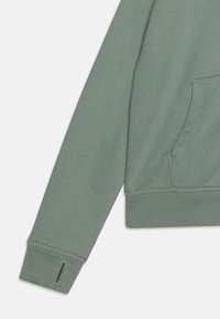 Zielona bluza z ribnowymi mankietami i dolnym wykończeniem, z kieszenią kangurką oraz teksturowanym materiałem. Rozcięcie po bokach mankietów jako dodatkowy detal.